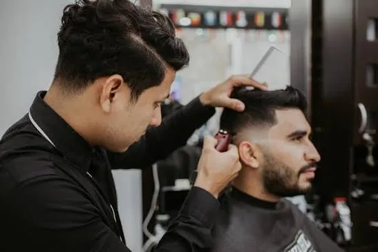Adam, barbier, en train de dégrader une coupe au peigne et à la tondeuse